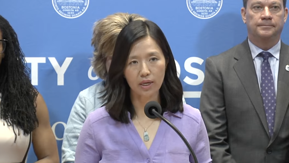 A woman stands at a podium with a microphone.
