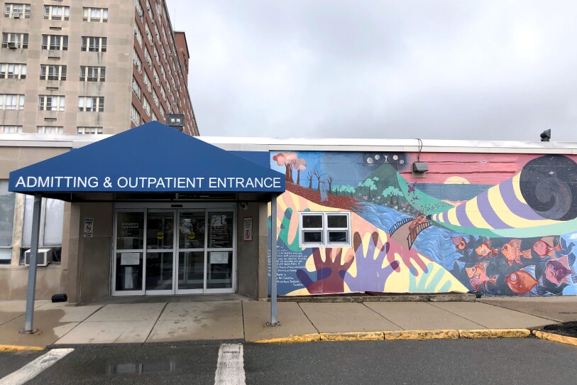 A blue awning covers a set of automatic doors. The short building is covered with a colorful mural.