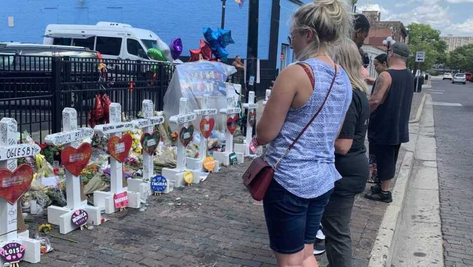 Onlookers in Dayton mourn the nine people who died when a gunman opened fire in a crowd outside a popular bar in the city's Oregon District earlier this month.