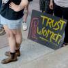 A sign sits with the words "Trust Women" rests on the ground.