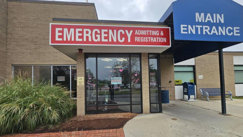Signs reading "emergency admitting and registration" and "main entrance" mark the doors of a small hospital.