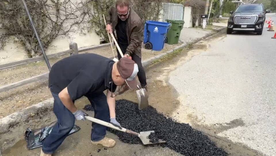 This video still image provided by Arnold Schwarzenegger's office, shows the former California governor (center back) repairing a pothole on a street in his Los Angeles neighborhood on Tuesday.