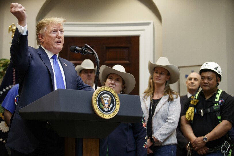 President Trump speaks at a presidential podium, as women in cowboy hats look on