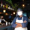 Portrait of a waiter with arms crossed and wearing protective face mask at restaurant