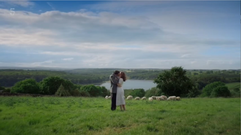 Helen and James kiss in a field