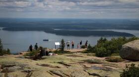 Park goers look over a cliff in Acadia National Park.