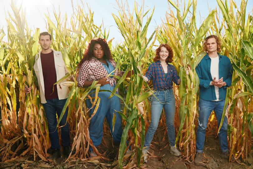 four members of the "Shucked" cast stand in a cornfield