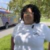 A woman stands in front of school bus.
