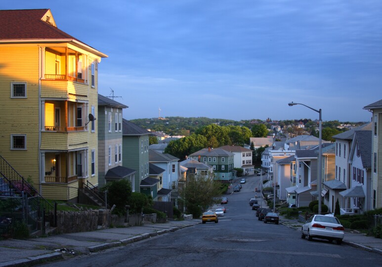 Shadows cast over a residential street lined with three-story apartment buildings.