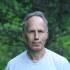 an older white man with gray hair wearing a grey t-shirt looks at the camera