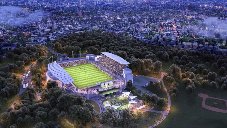 A large stadium is nestled in a park, with Boston in the backdrop.
