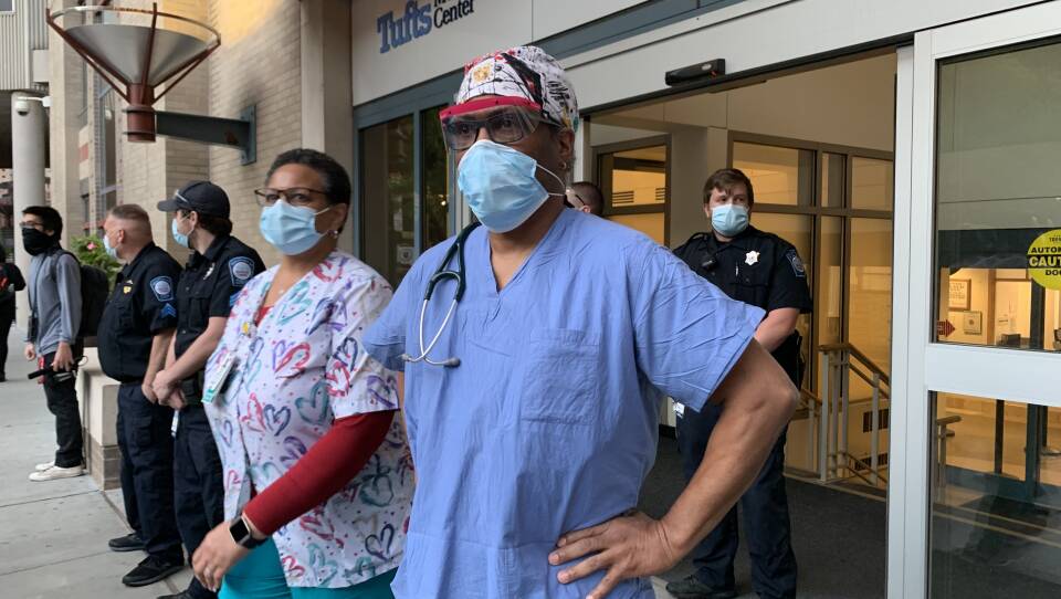 Emergency Room physician Dr. Furman Walls stands outside the Tufts Medical emergency room doors, watching a parade march by on May 31, 2020