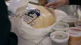 A person's hand puts a store-bought turkey into a large plastic bag at the checkout counter of a grocery store.