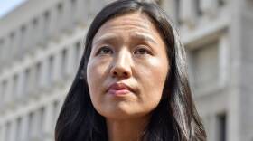 Michelle Wu looks up as she stands outside the City Hall building.