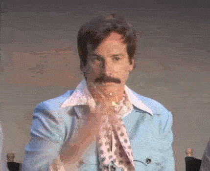 A man dramatically throws a spray of glitter in the air in front of his face