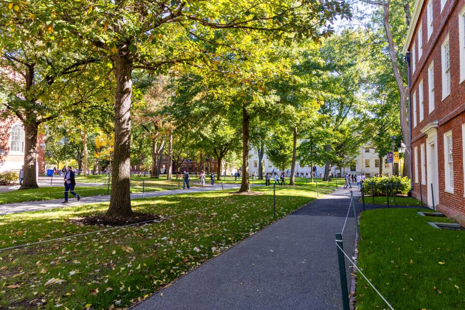 Paved paths criss cross a New England college quad. Brick buildings are on its edges.
