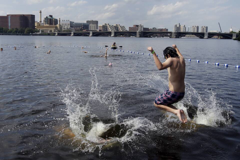 A boy in swim trunks jumps into the Charles River in Boston, Mass.