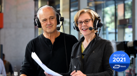 A man and woman wear headsets with microphones.
