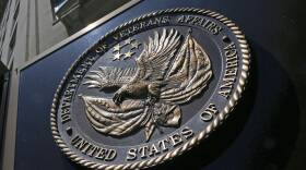 A seal with a bald eagle holding a Betsy Ross flag and modern American flag, encircled with the words "Department of Veteran Affairs"