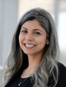 A headshot of a smiling woman with gray hair.