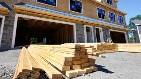 A pile of lumber in front of a home under construction.