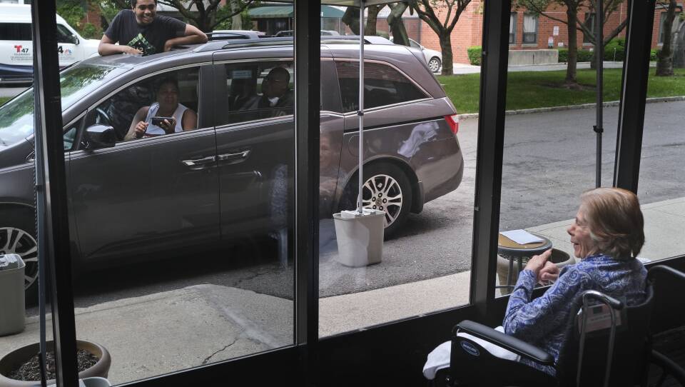 Gloria DeSoto, 92, right, visits with her family, in their car, from a window of the Hebrew Home at Riverdale, in New York, last month.