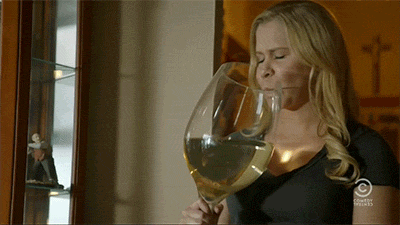 A woman drinks from a giant wine glass