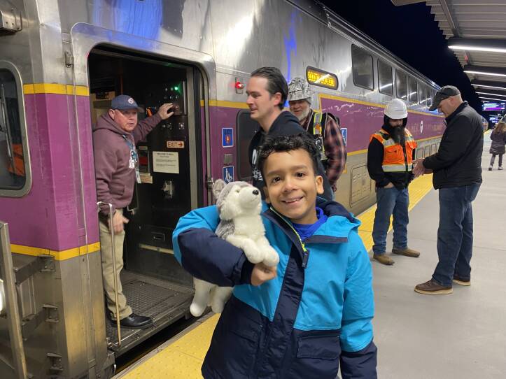 A young boy stands outside of a train