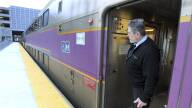 A conductor on a commuter rail train at a station looks out over the platform.