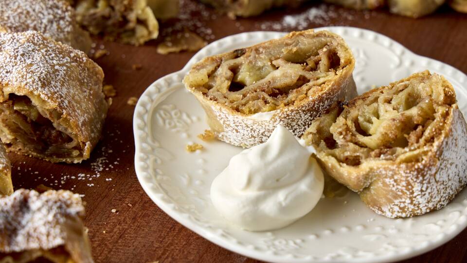 Plate with two slices of rolled pastry dusted with powdered sugar with whipped cream on the side