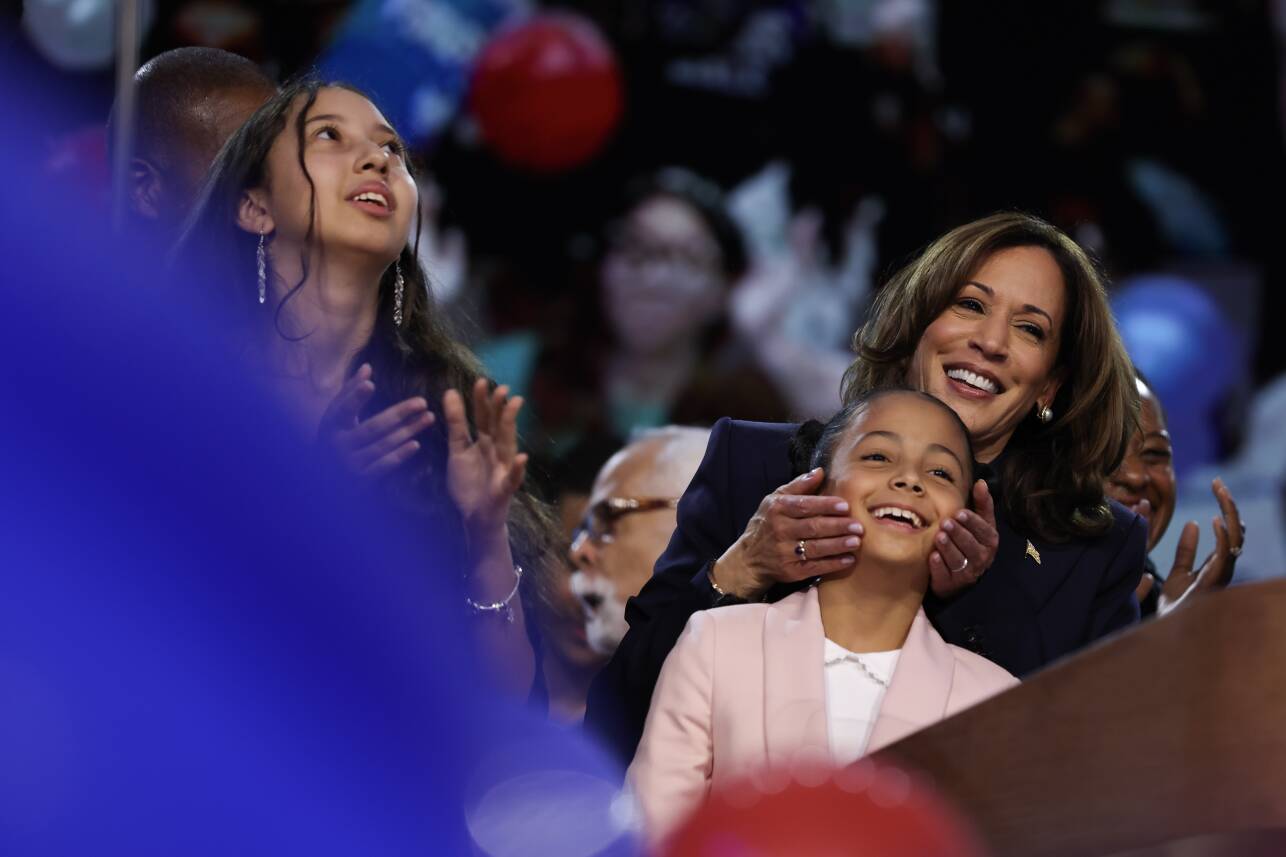 Kamala Harris holds a smiling little girl's cheeks