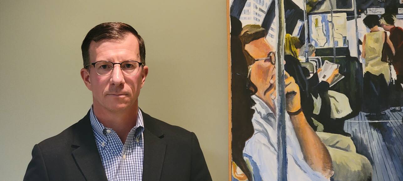 A portrait of a white man wearing a suit jacket and glasses.
