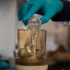Kat Yetka (left) pours the wastewater sample over a filter (right), negatively-charged to better capture COVID virus particles.