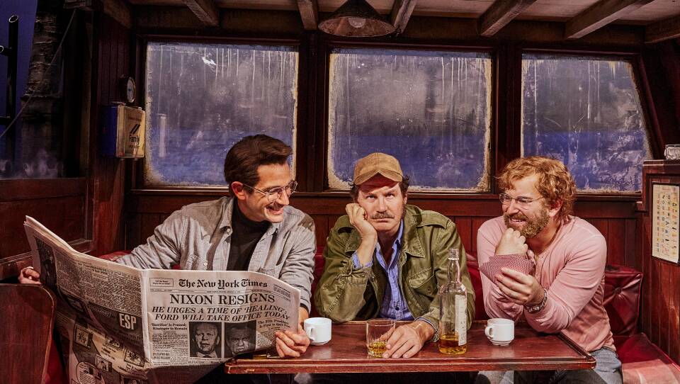 Colin Donnell, Ian Shaw, and Alex Brightman sit at a table in a production photo from "The Shark Is Broken"