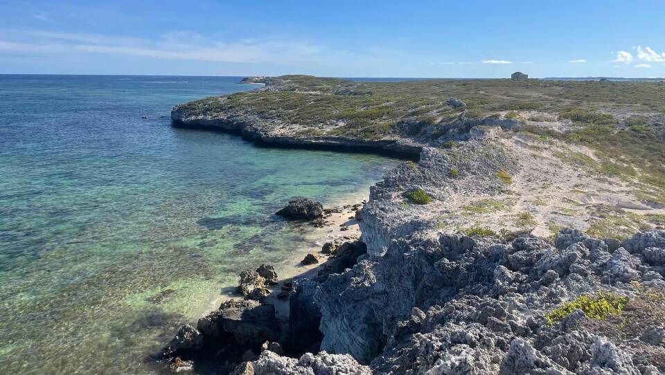 A rocky beach with clear blue water.
