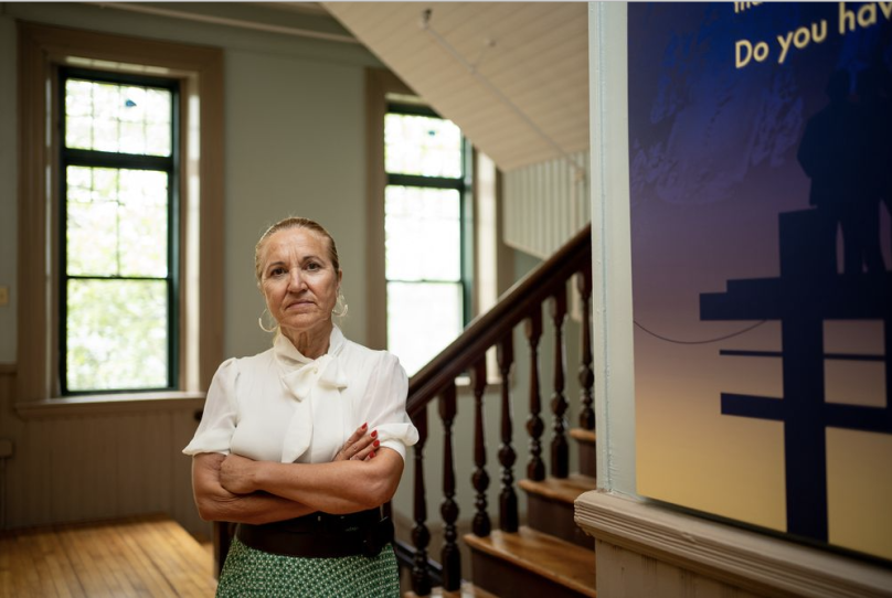 A woman who looks disappointed poses for a photo, her arms crossed
