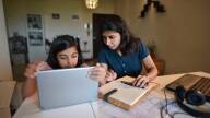 Woman working from home while daughter using digital tablet