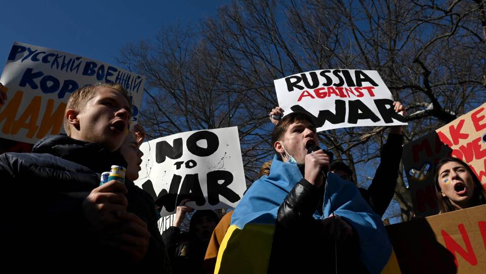 Students stand outside holding signs.