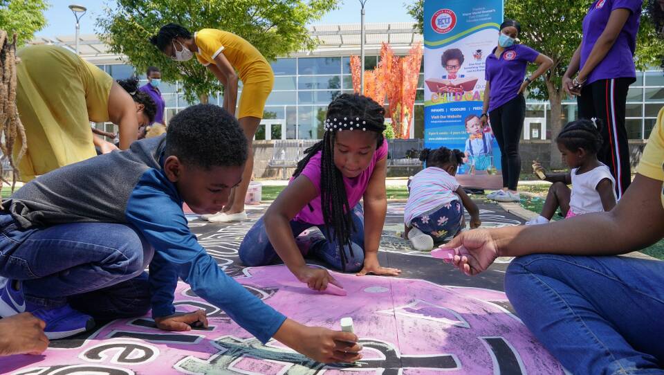 Children and teachers from the KU Kids Deanwood child care center in Washington, D.C., complete a mural in celebration of the launch of the Child Tax Credit.
