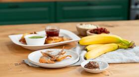Platters of wontons, some with powdered sugar next to a bowl of Nutella and some banana, and some on a plate with bowls of marinara and pesto
