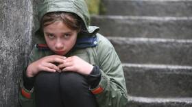 Child wearing green coat sitting on stairs
