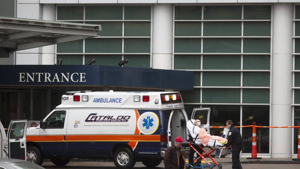 A patient on a gurney is brought out of an ambulance.