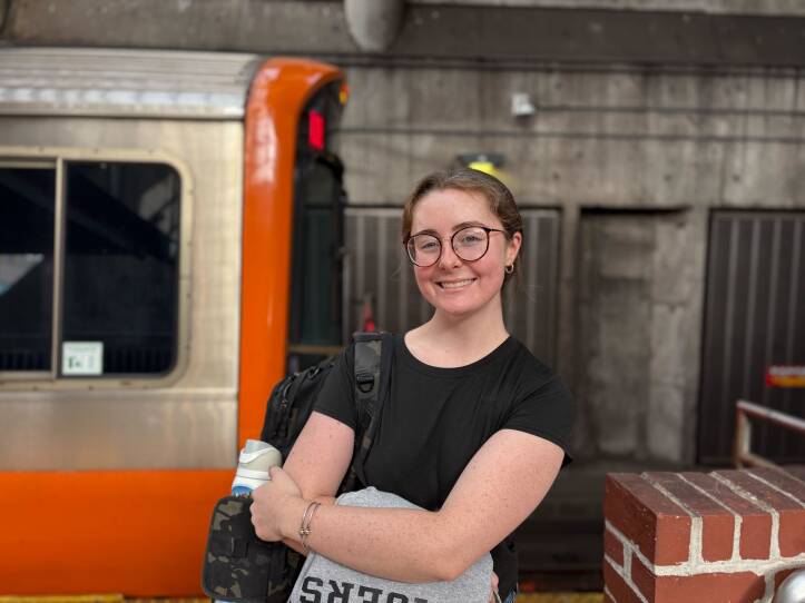 A woman stands in front of a train on a platform