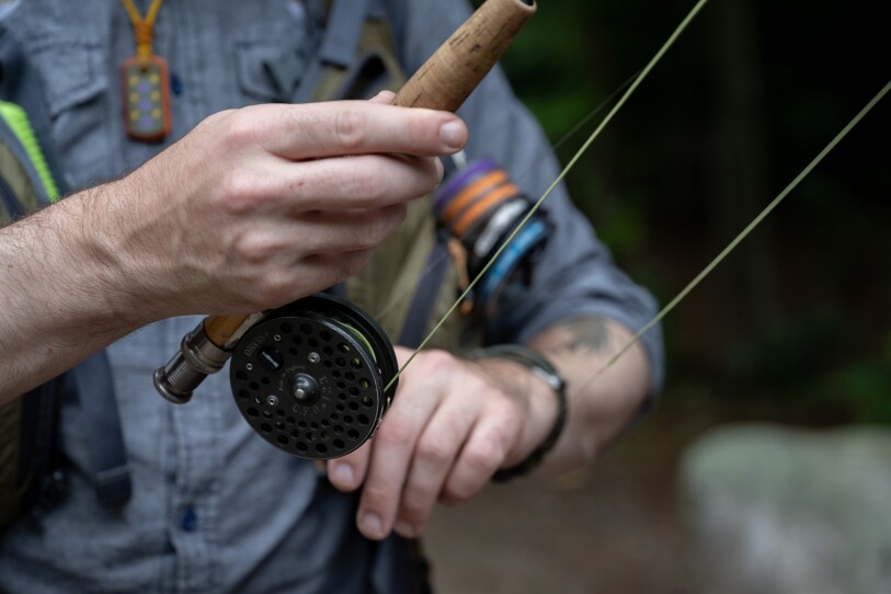 A man winds up fishing line at the base of his rod.