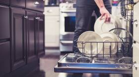Midsection Of Man Keeping Plates In Dish Washer