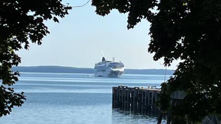 A large cruise ship approaches a wood dock.