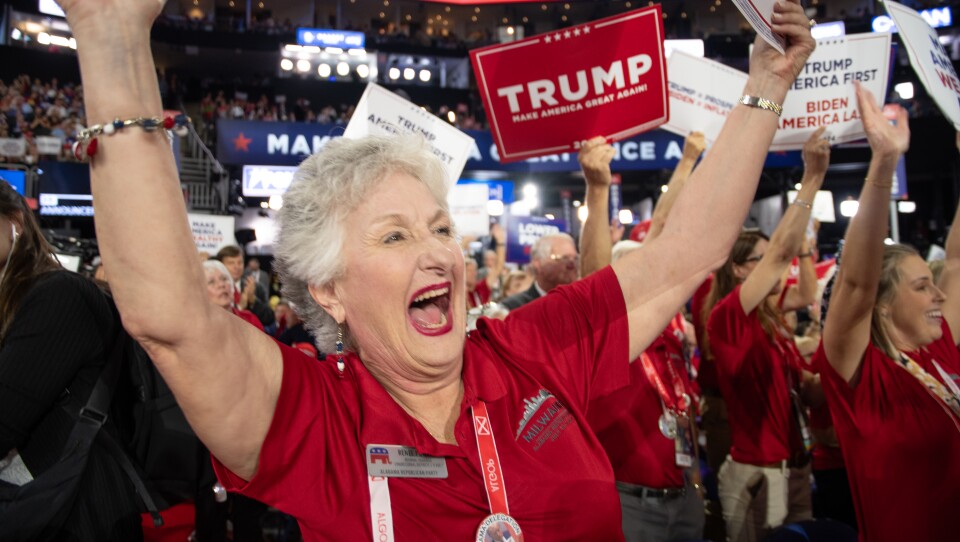 A woman in a red polo shirt yells in excitement on the convention floor.