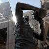 A photo of a sculpture depicting Bill Russell taken from below, the sun shining behind his head.