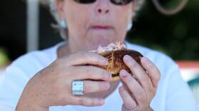 A woman holds up a lobster roll to eat.