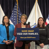 The governor speaks during a press conference over a podium that reads "Save SNAP. Feed our families." And the URL "Mass.gov/SNAPFreeze."